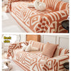 Kuscheldecke mit geometrischen Mustern in Orange und Weiß und cremefarbenen Quasten.