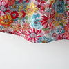 A close-up of a baby girl's floral print dress with a matching hat featuring colorful flowers.