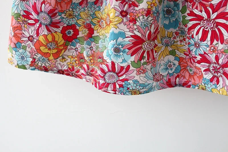 A close-up of a baby girl's floral print dress with a matching hat featuring colorful flowers.