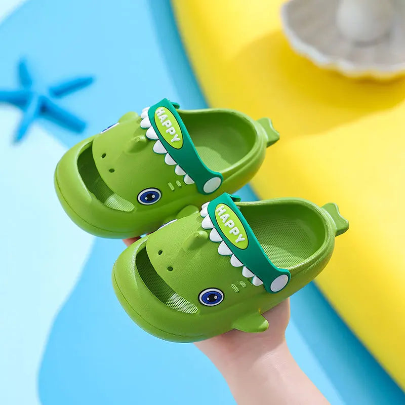 A pair of green shark clog sandals for kids with a happy face design