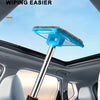 A hand holds a telescopic windshield cleaning brush with a blue head, positioned inside a car cabin.