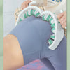 A person is using a white full body massage roller with green handles on their leg.
