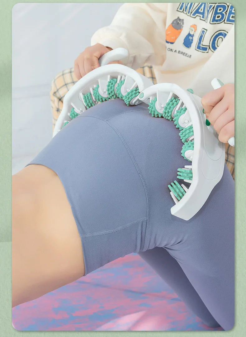 A person is using a white full body massage roller with green handles on their leg.