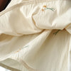 A close-up of a cream-colored girls' summer dress fabric featuring delicate floral embroidery.