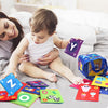 A baby is shown interacting with colorful alphabet and number flash cards and a storage bag on a gray blanket.