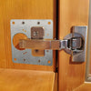Stainless steel cabinet door hinge repair plate kit with screws attached to a wooden door frame.