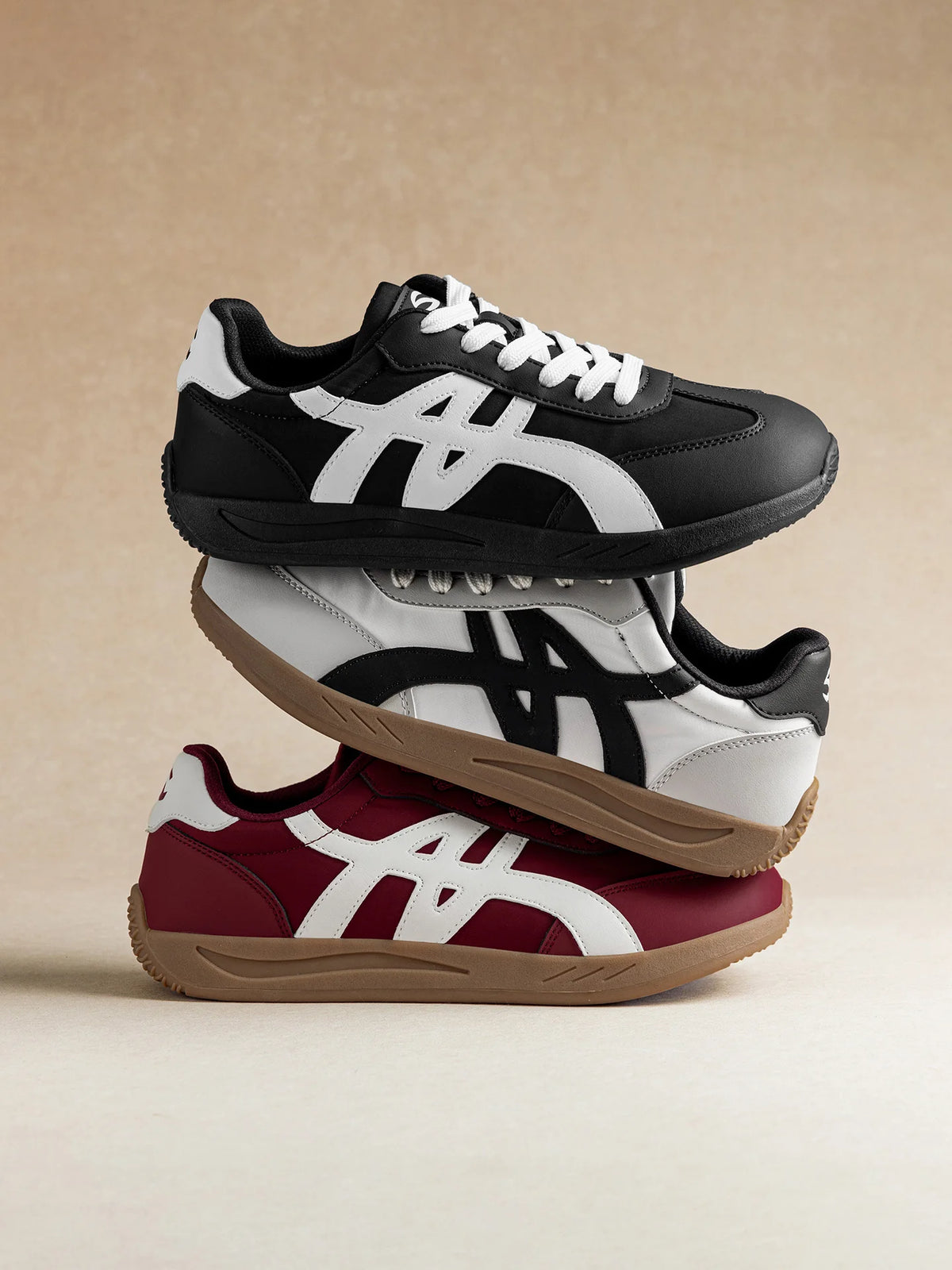 Ein Paar Adidas Originals Sneaker in Schwarz und Weiß mit einem bordeauxfarbenen Akzent, von der Seite gezeigt.