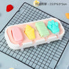 A white silicone popsicle mold tray holds four brightly colored popsicles: pink, yellow, green, and blue.
