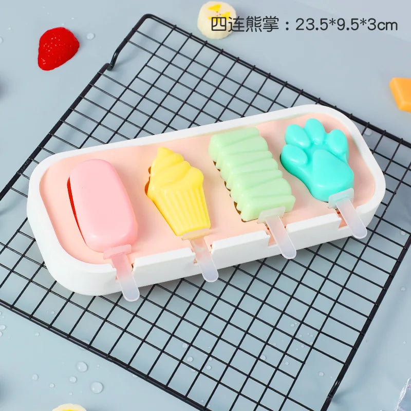 A white silicone popsicle mold tray holds four brightly colored popsicles: pink, yellow, green, and blue.