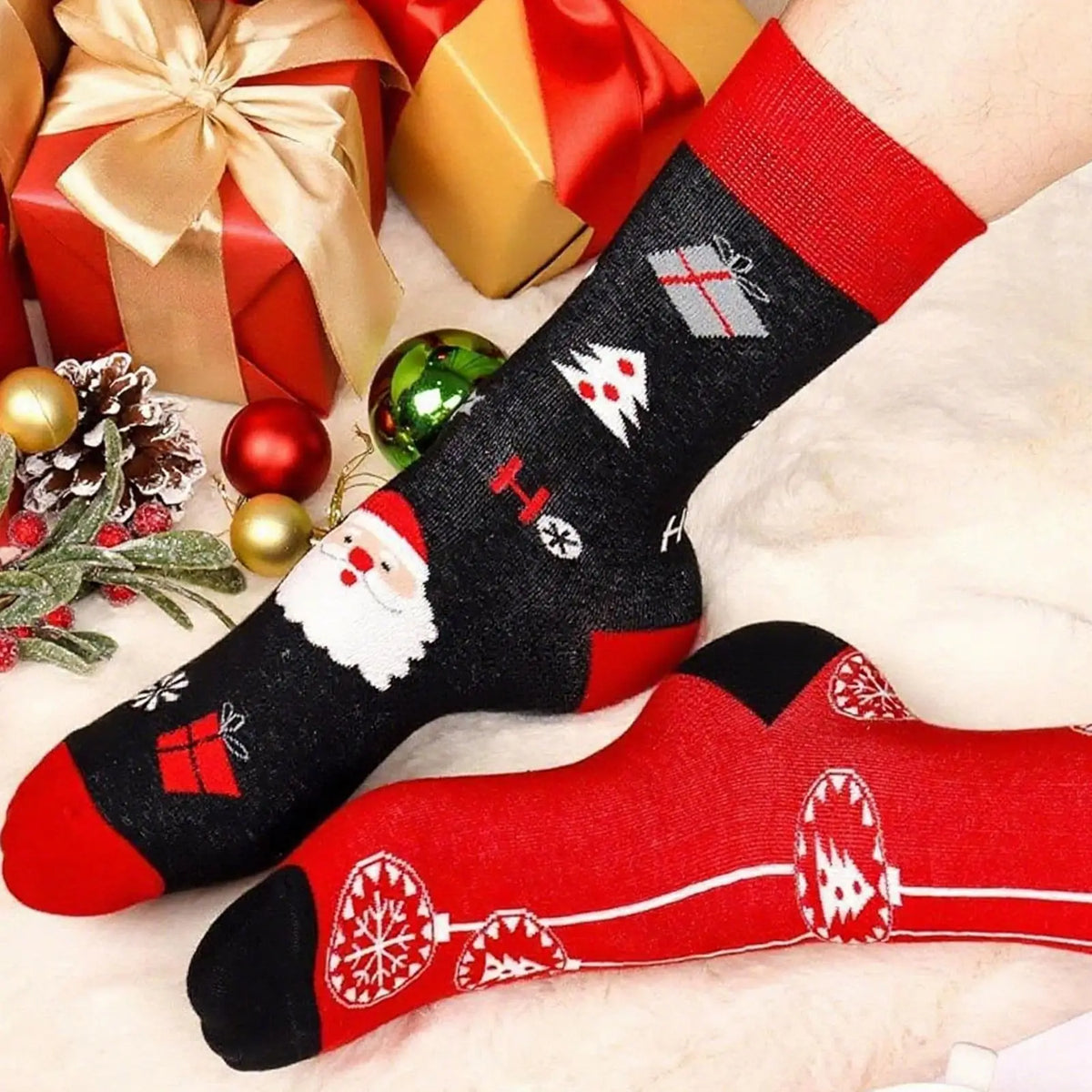 A pair of festive Christmas socks with red and black patterns lying on a white surface.