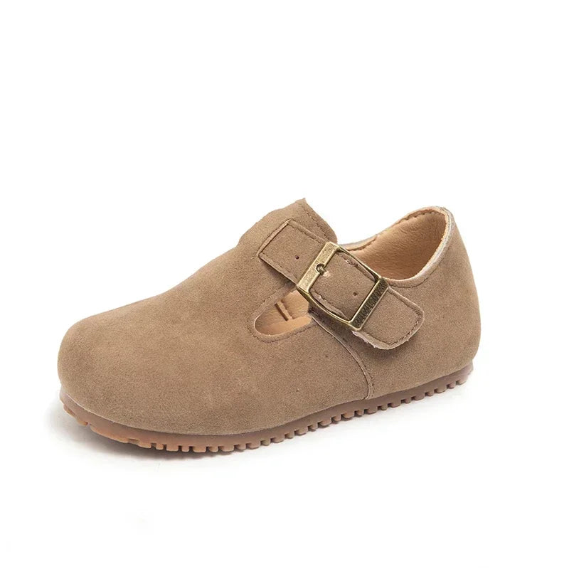 A tan suede moccasin shoe for a child with a hook-and-loop closure.