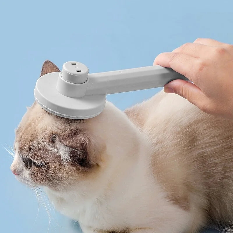 A hand is using a white self-cleaning pet grooming comb on the head of a cat.