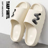 A pair of beige soft tarp and elastic slide slippers with a black wavy design.