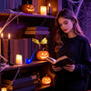 Une femme lit un livre près d'une étagère décorée de citrouilles et de bougies, éclairée par une lumière LED chaleureuse.