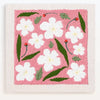 Pink pude broderi med hvide blomster og grønne blade på beige baggrund.