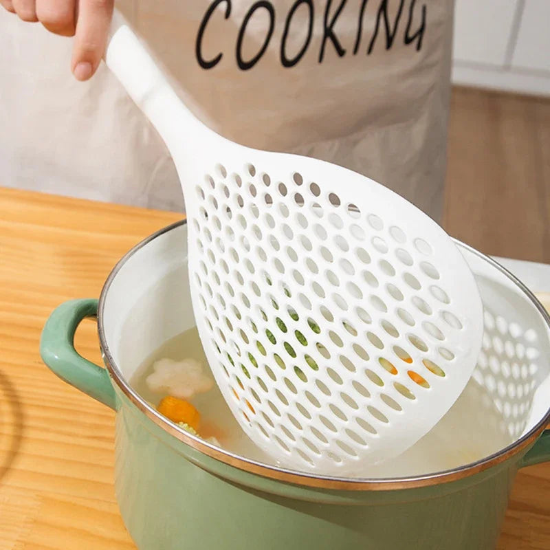 A white long-handled kitchen strainer spoon is shown scooping ingredients from a green pot.