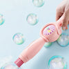 A hand is using a pink smoke bubble wand to produce and control the size of iridescent bubbles.