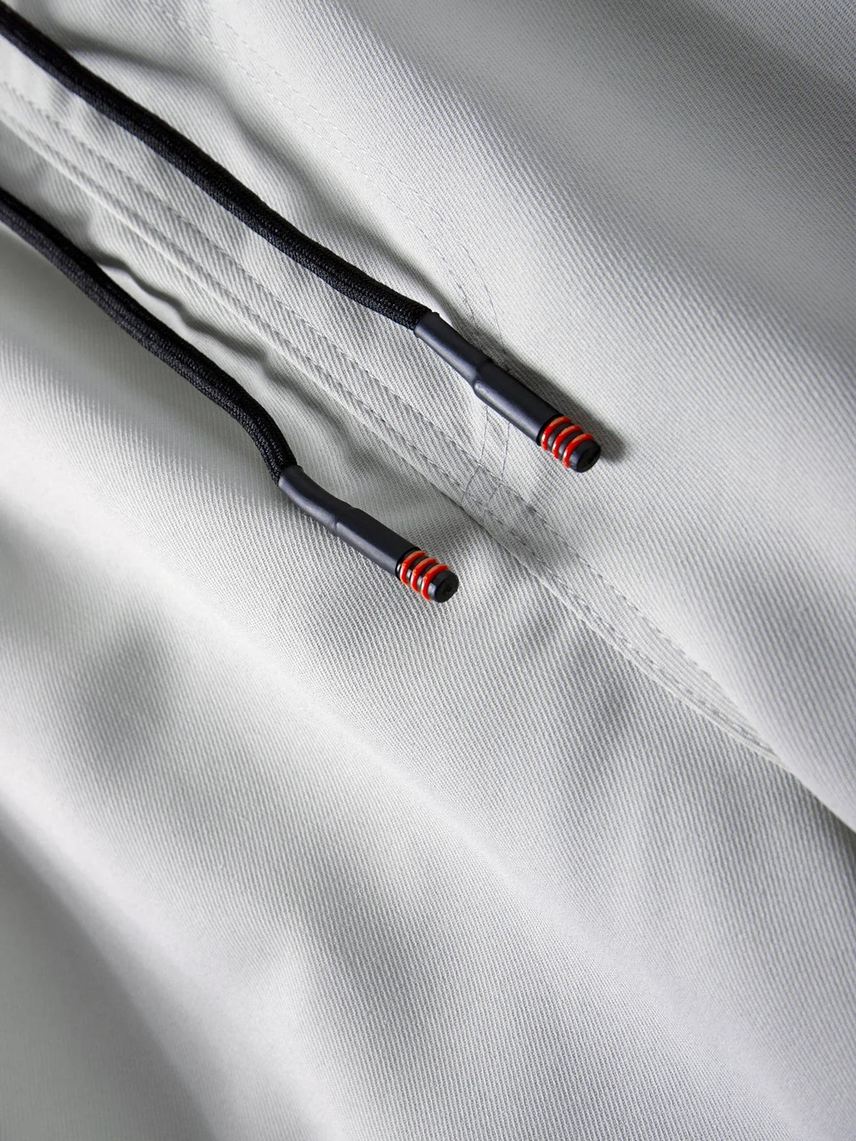 Close-up of black cord with red accents attached to a light gray fabric, showing an adjustable feature on men's cargo joggers