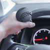 Main tenant une poignée de volant noire conçue pour rotation à 360° dans l'habitacle d'une voiture.