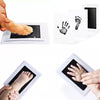 Inkless baby handprint and footprint keepsake kit showing various impressions on white paper.