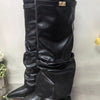 A pair of black knee-high chunky heel boots with a metal buckle displayed against a light background.