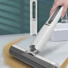 A hand is holding a white compact self-squeezing mini mop with a clear cleaning head on a white surface.