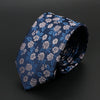 Corbata de jacquard azul marino con estampado floral y detalles plateados, mostrada doblada.