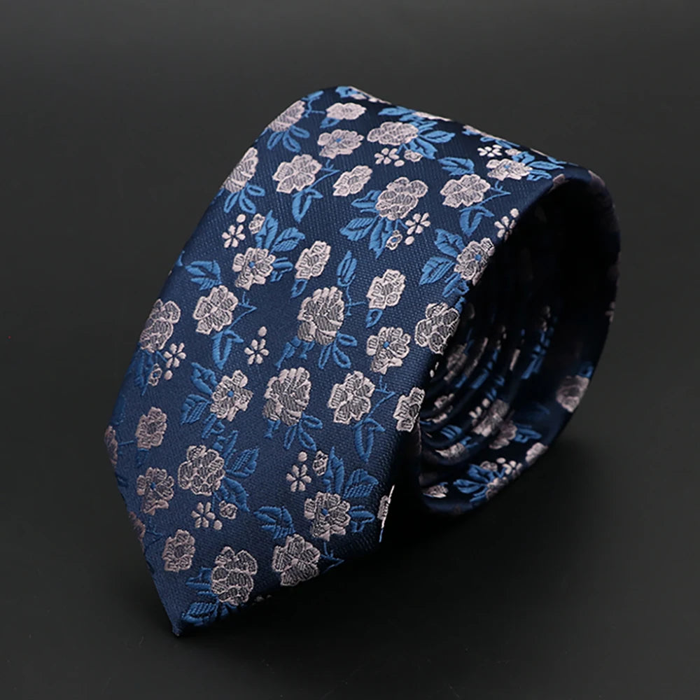Corbata de jacquard azul marino con estampado floral y detalles plateados, mostrada doblada.