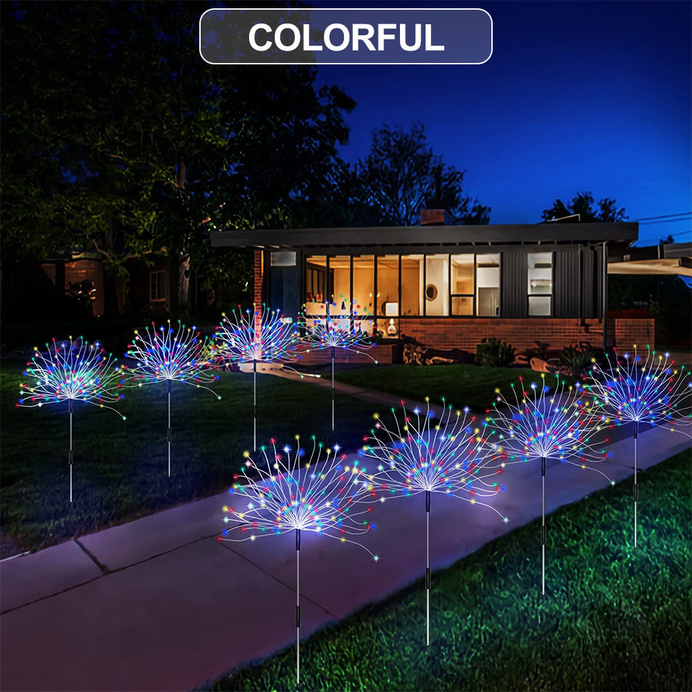 Colorful solar fireworks lawn lights illuminating a backyard landscape at night.