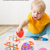 A toddler is playing with a pink plastic sorting toy filled with colorful fruit blocks on a light blue mat.
