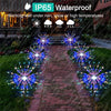 A row of colorful fireworks lawn lights illuminating a brick pathway in a garden setting.
