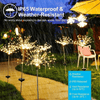 A display of bright golden fireworks lights illuminating a garden scene during a rain shower.